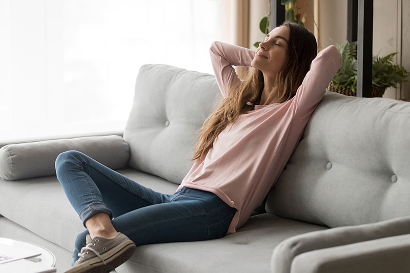 Woman sitting comfortably on sofa because her stomach pain and Nausea are gone